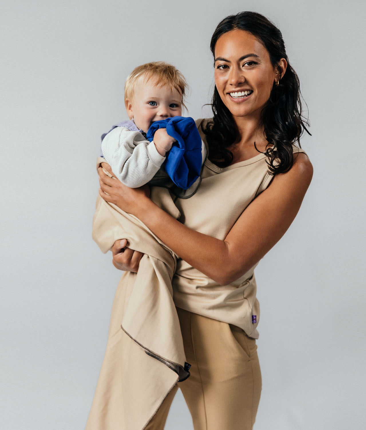 Woman holding a baby in a beige EMF protective blanket Leblok