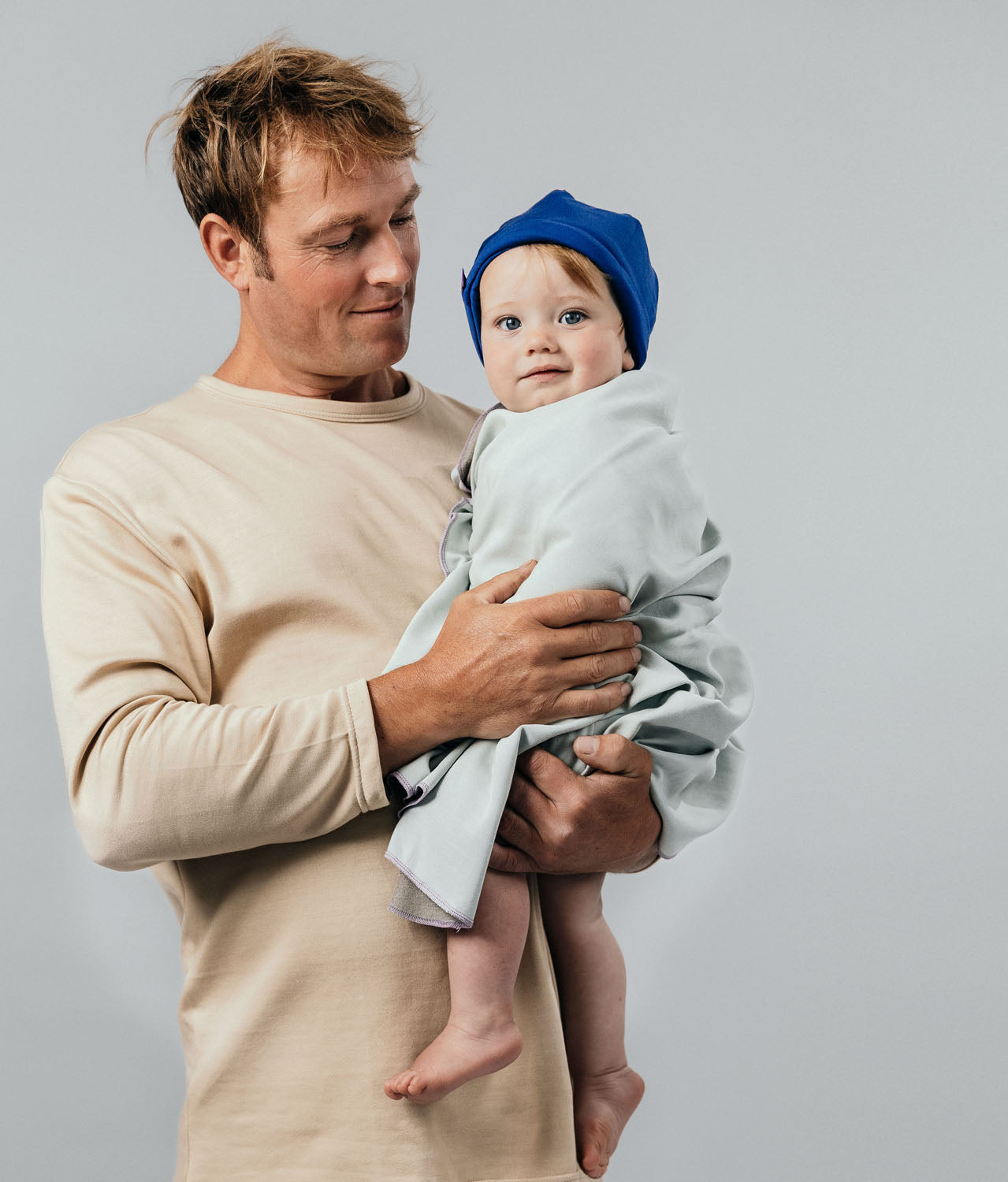 Man holding a baby wrapped in an EMF shielding blanket Leblok