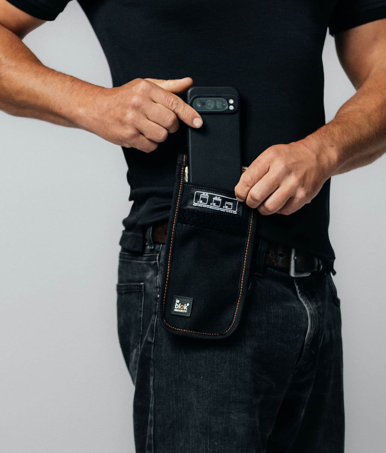 Phone faraday bag Leblok Security attached to belt - a man placing phone inside the bag